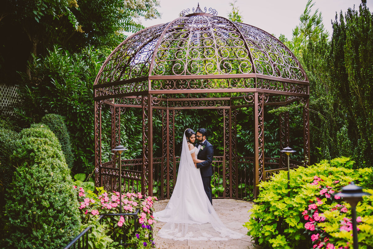 An indian christian malayali bride and groom on their wedding day together under the birdcage gazebo at leonard's palazzo