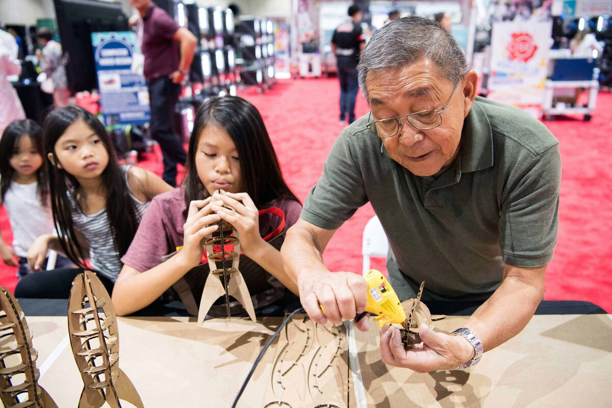 A man glues pieces of a rocket together at fun expo booth