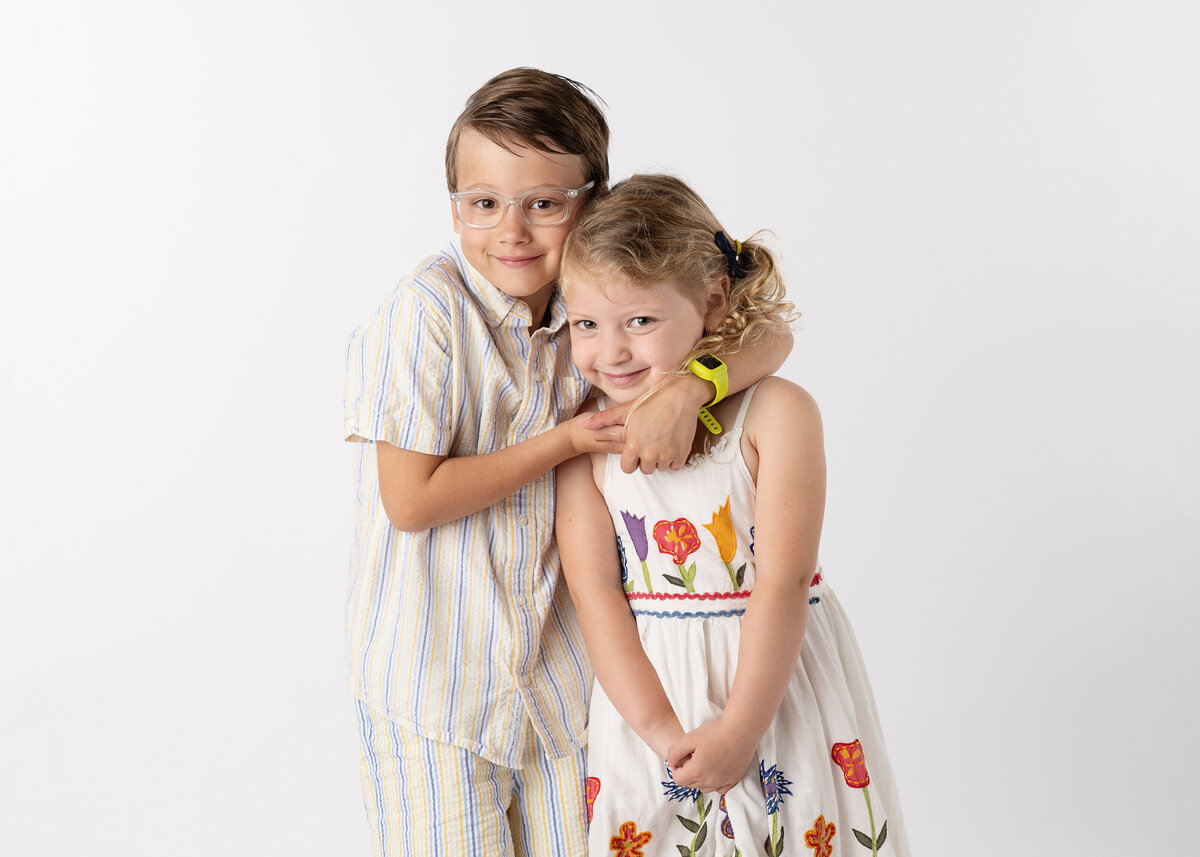 A school-aged brother and sister posing for their school picture.