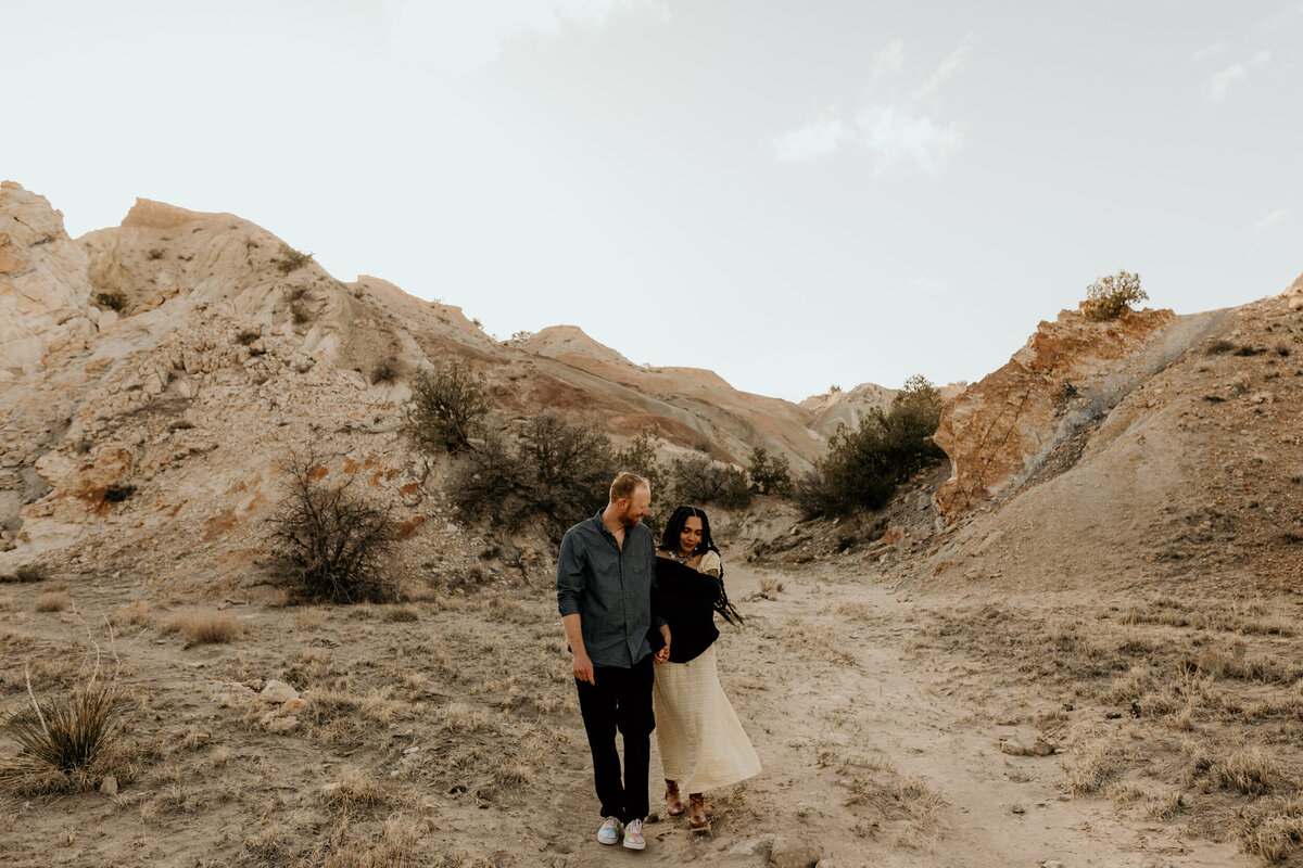 man and woman walking through the desert