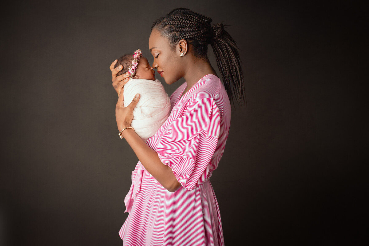 mother dressed in pink snuggling her newborn baby girl, hamilton, ON newborn studio