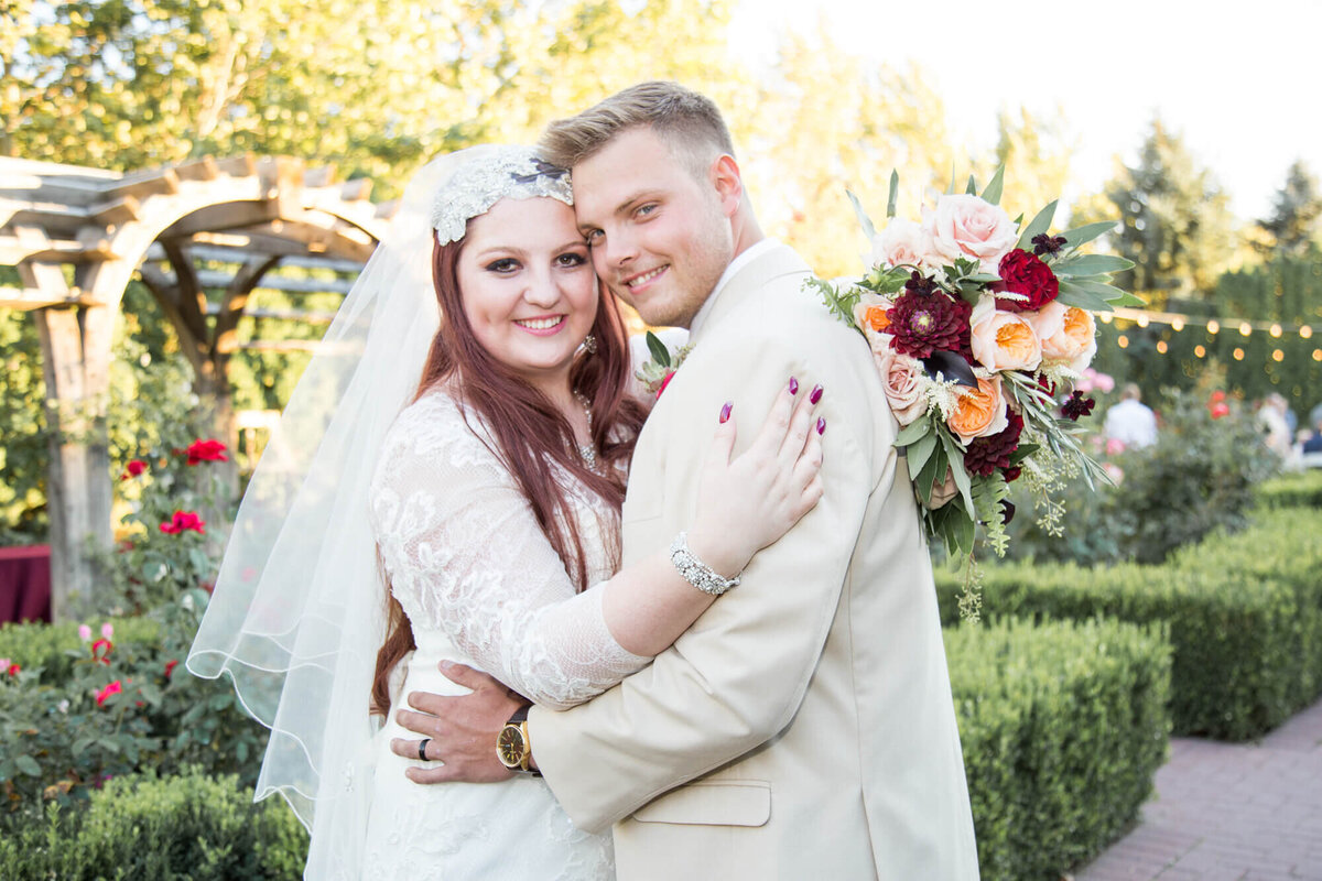 bride and groom smiling in a green rose garden