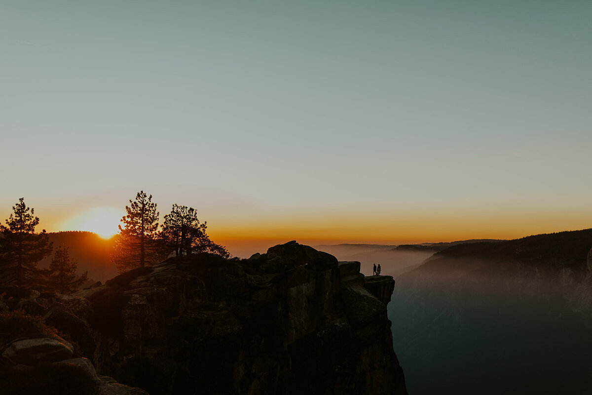couple standing on the edge of a mountain at sunrise
