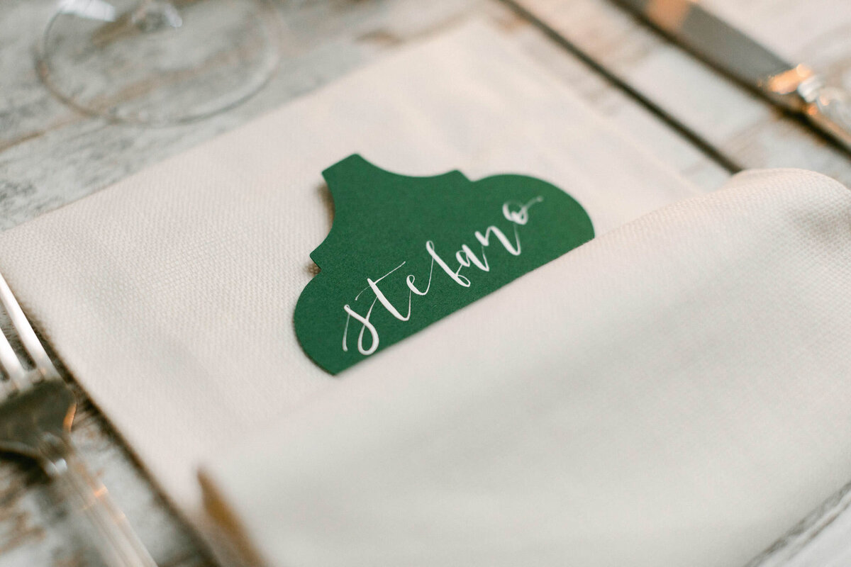 green name card on table with Stefano written in white cursive