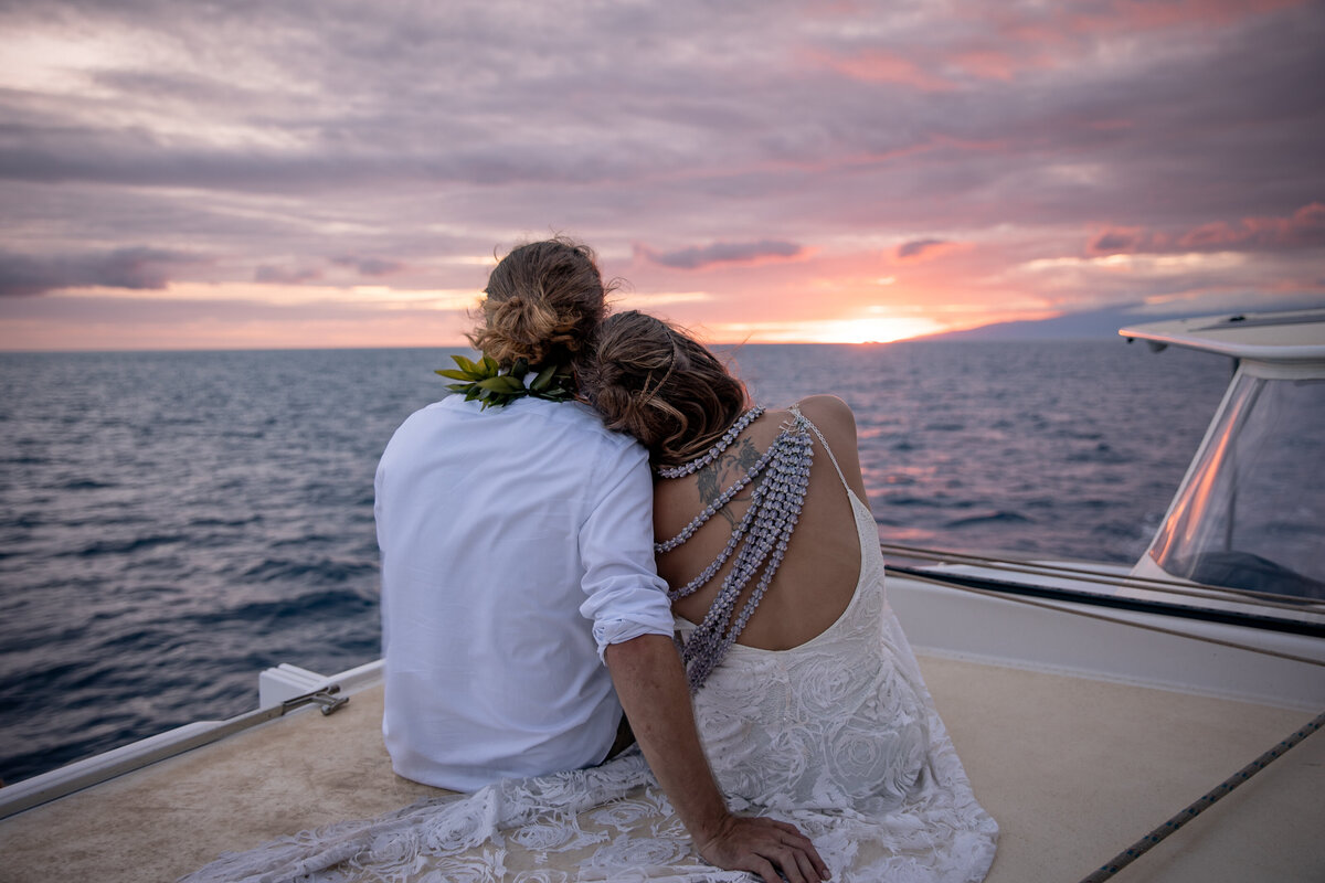 Maui Wedding Photographer captures bride and groom sitting on boat at sunset