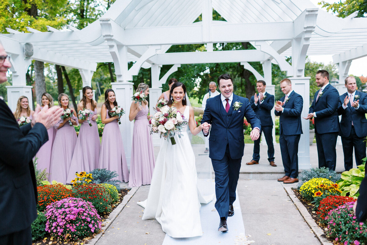 Newlyweds walking down the aisle with joy after their ceremony at Bearpath Golf & Country Club