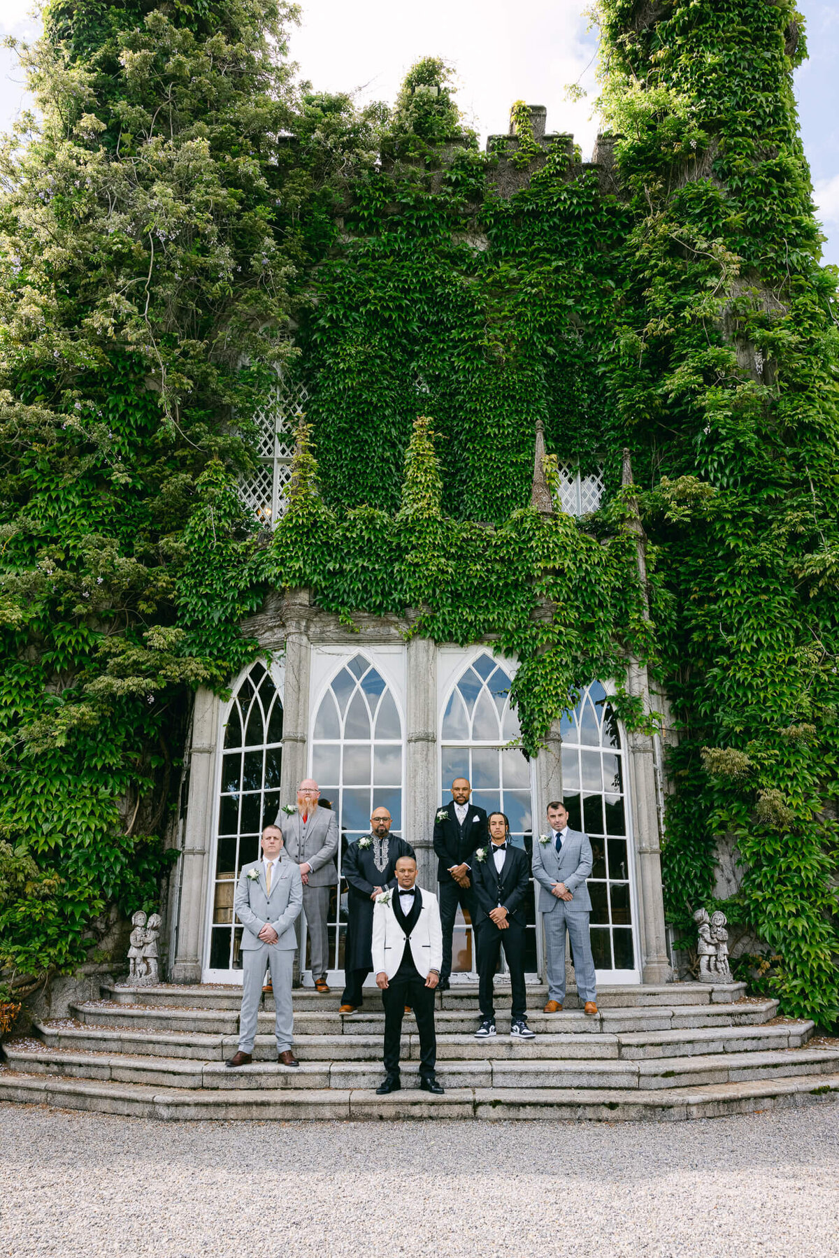 A wedding photo of the groom and his groomsmen posing in front of Luttrellstown Castle in Ireland