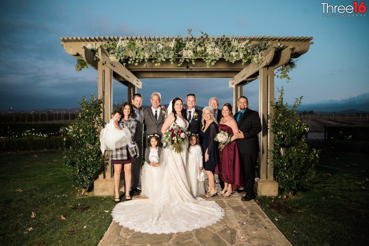 Newly married couple posing with their families under the gazebo