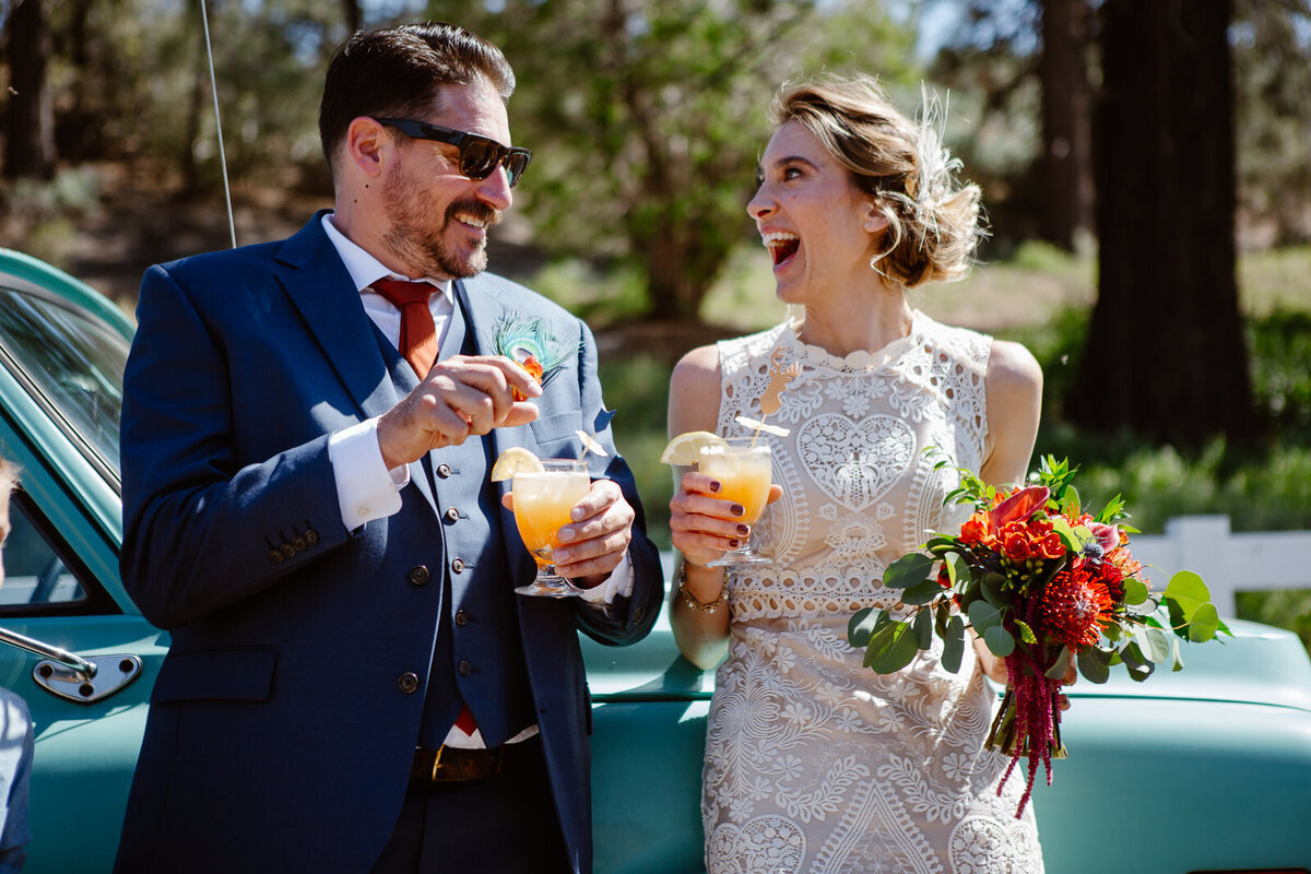 Ali and Brian hold drinks, laughing outdoors.