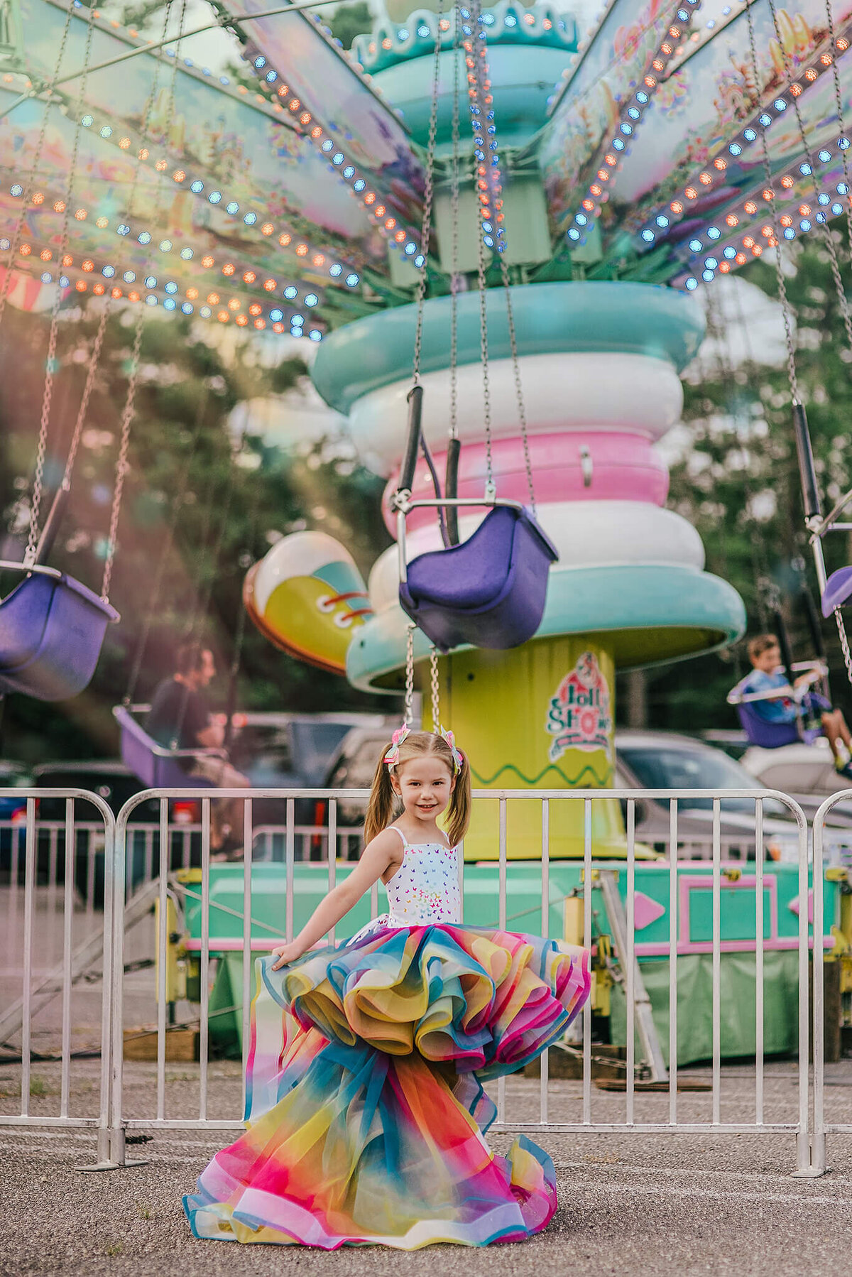 girl in pigtails wearing a rainbow dress in front of a carnival ride near Annapolis Maryland