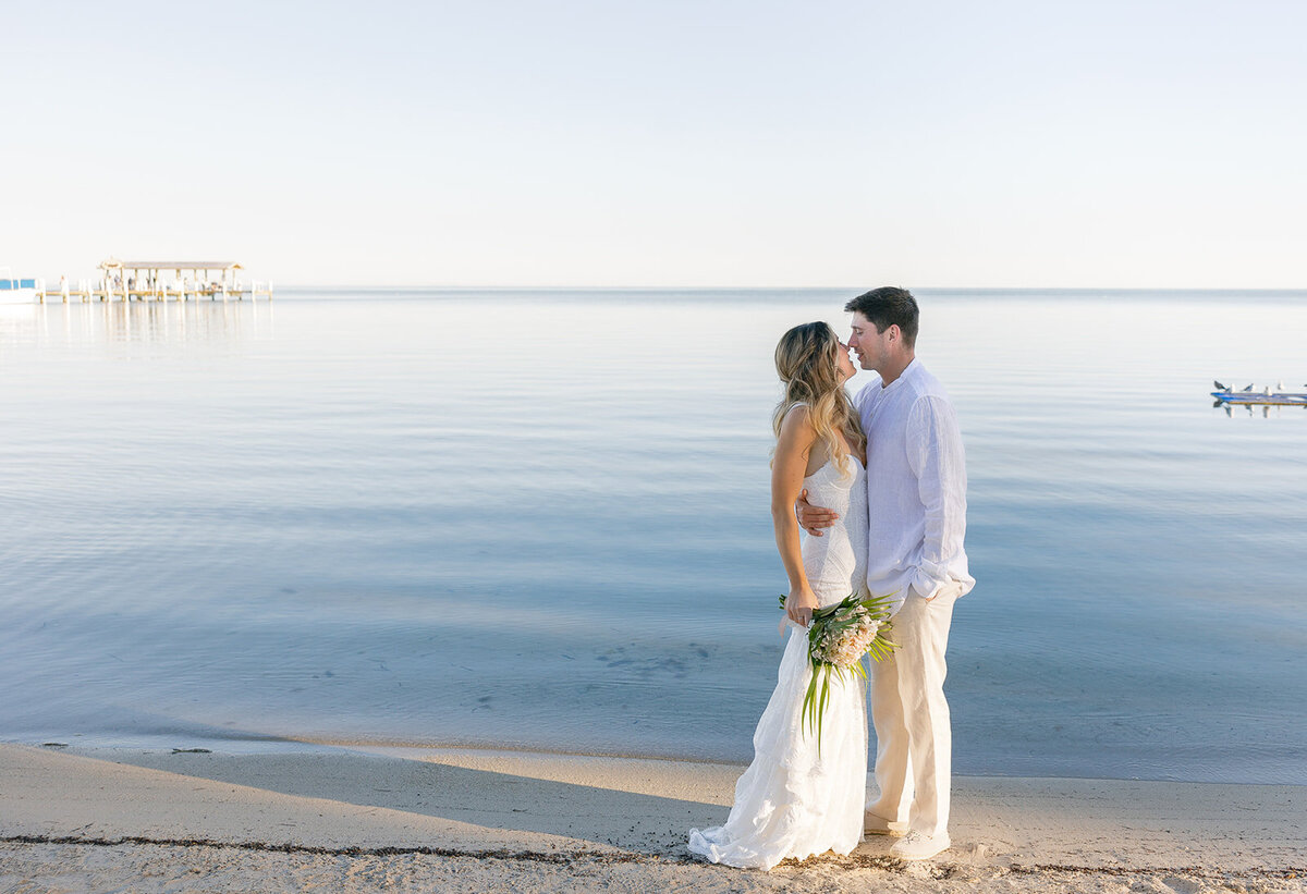  Bride Laura and groom Abraham sharing a romantic kiss by the ocean at their Miami destination wedding.