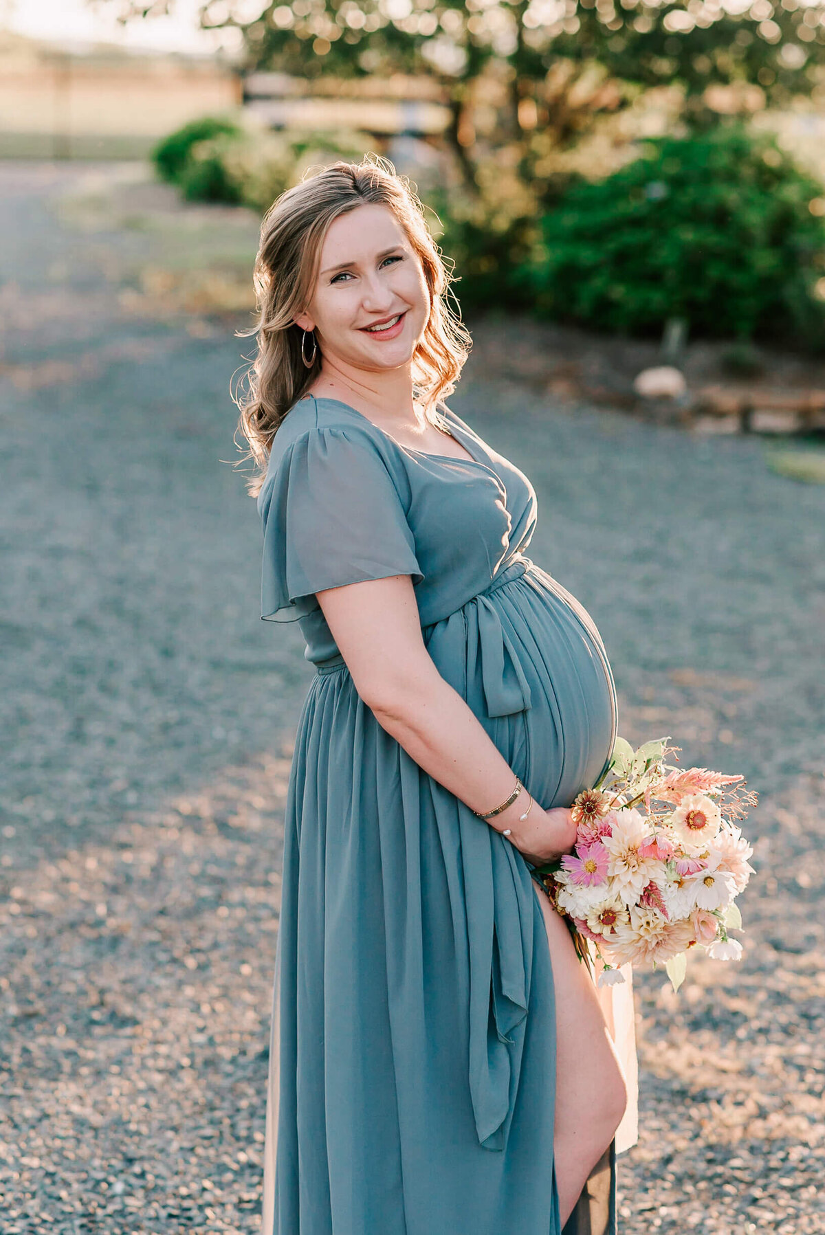 A woman holding her bump and a bouquet in Waterford VA