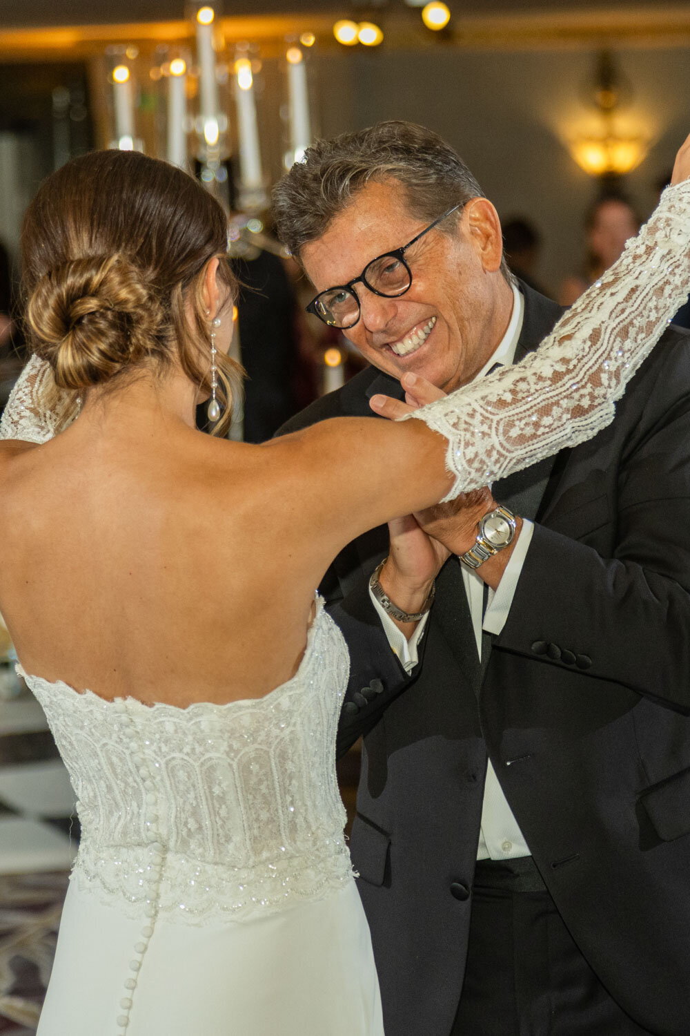 A man in a suit is dancing with a woman in a white dress