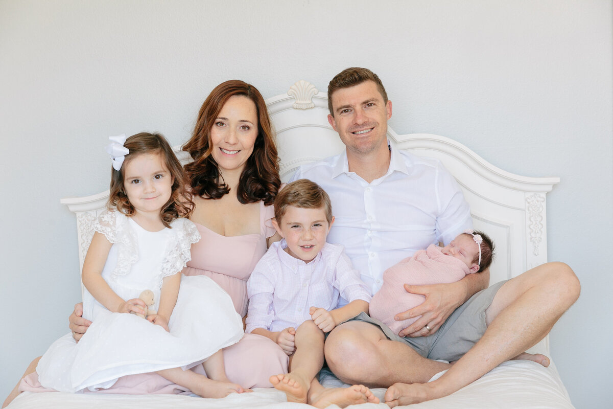 A family sitting on a bed together smiling