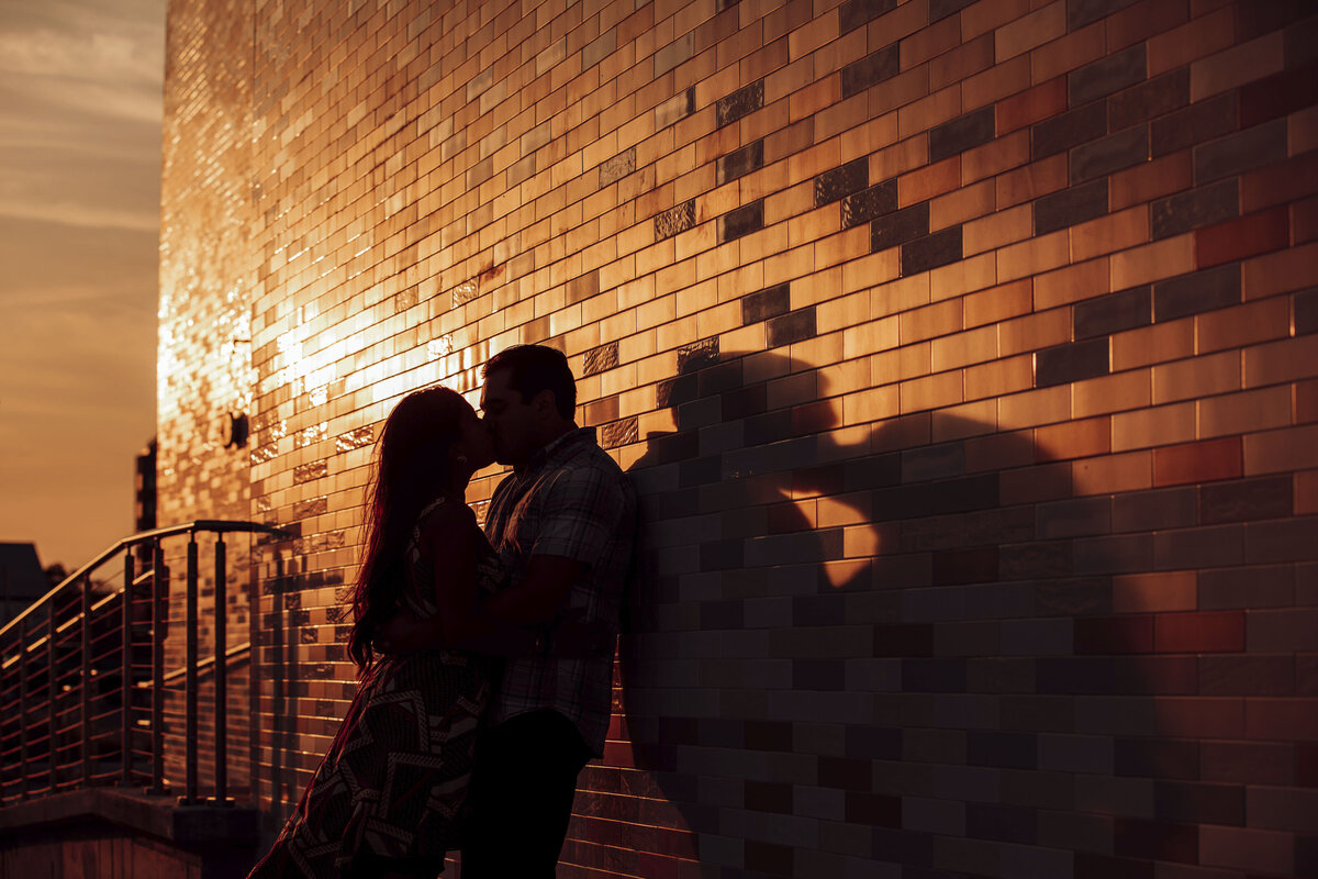 Engaged couple kissing in silhouette at sunset during Asbury Park New Jersey engagement shoot