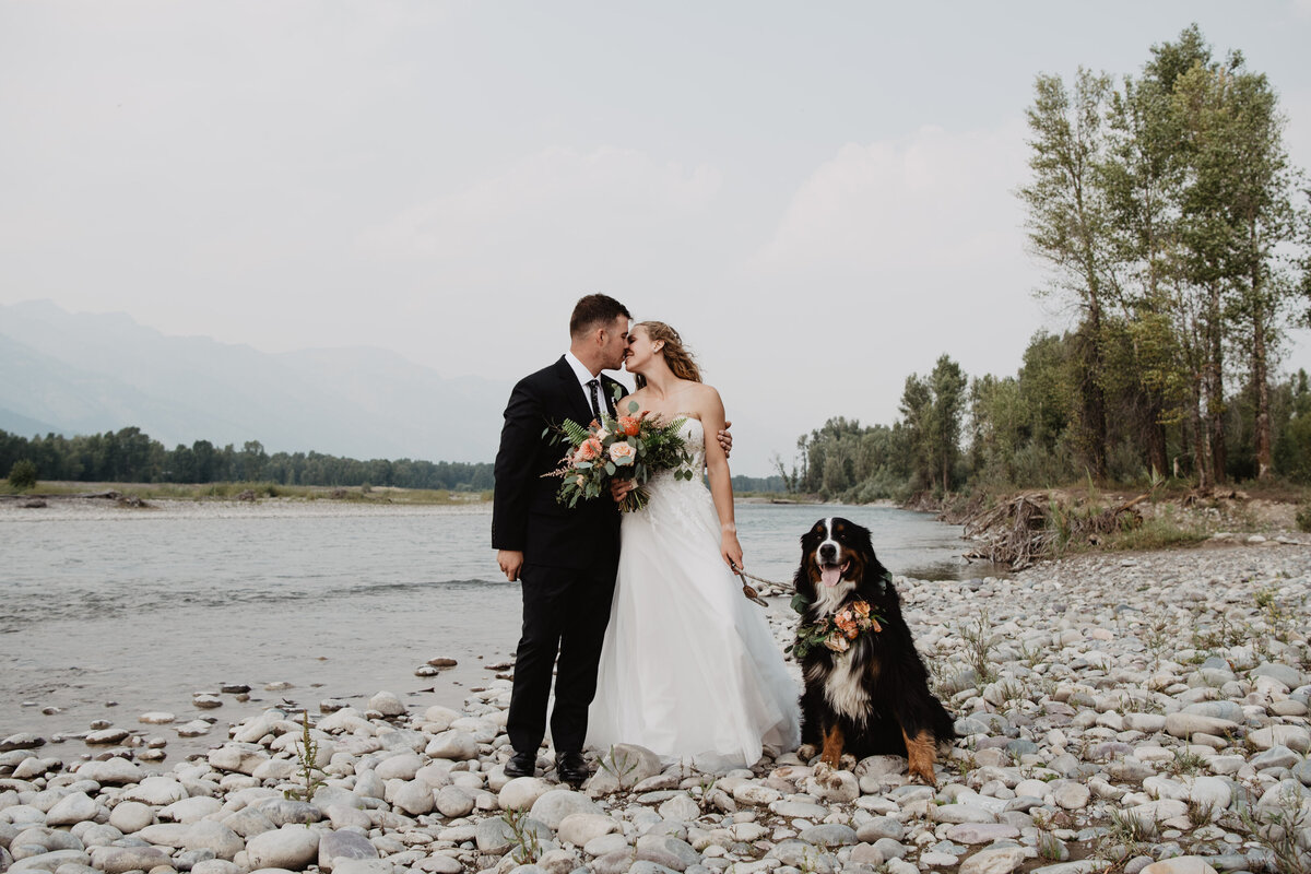 Jackson Hole Photographers capture bride and groom kissing while holding dog