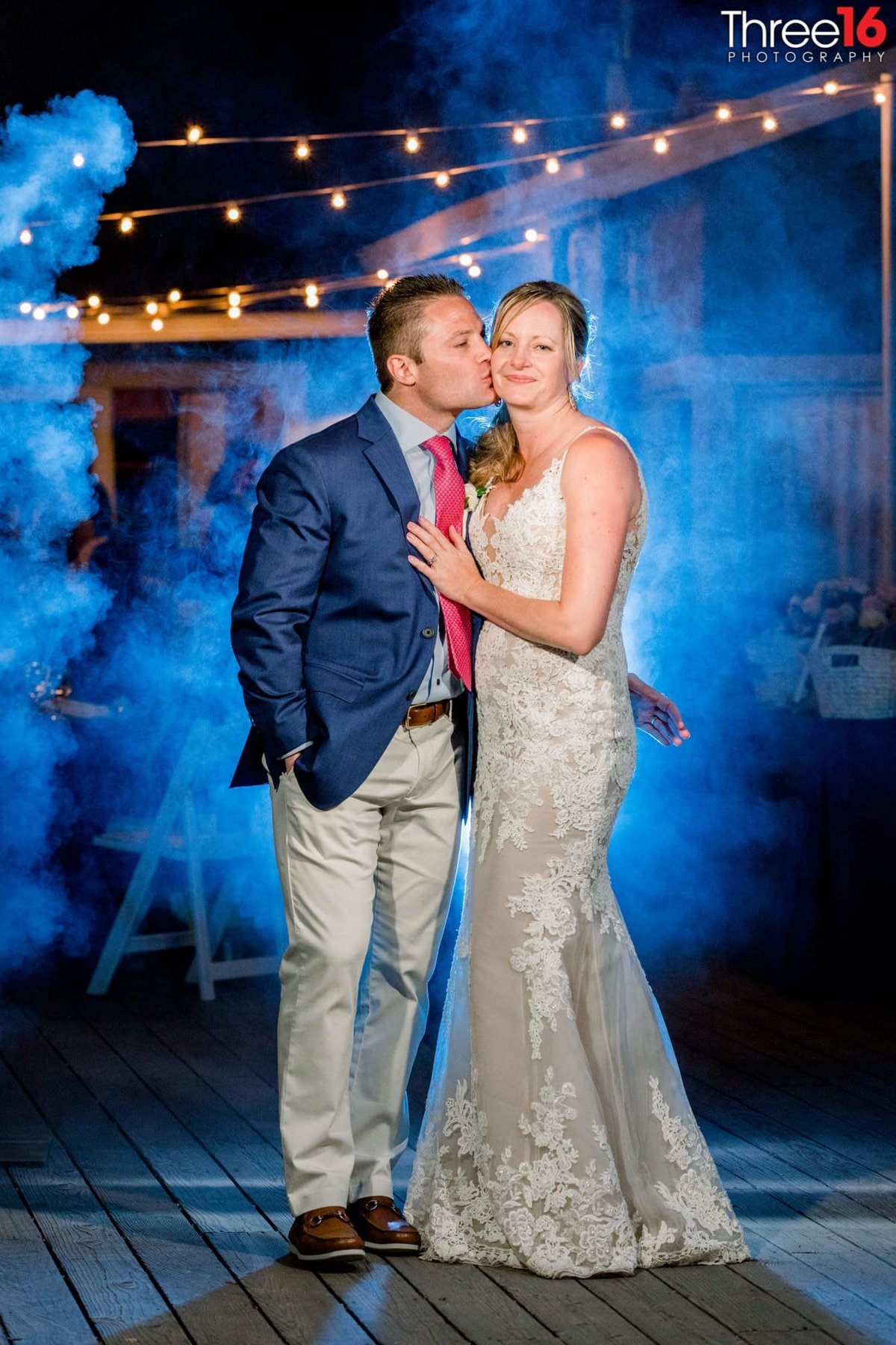 Husband kisses his Wife's cheek  while a puff of smoke is behind them