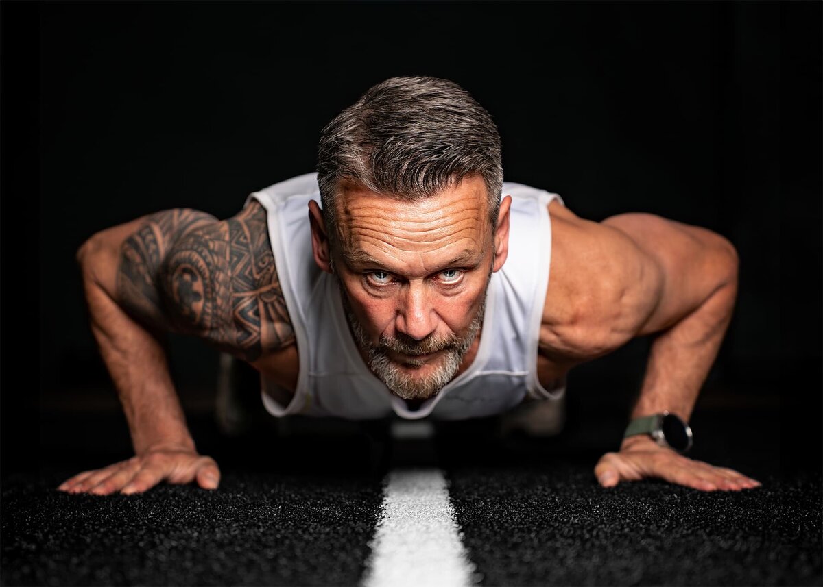 Sportfotografering med en man som gör en armhävning på ett gym