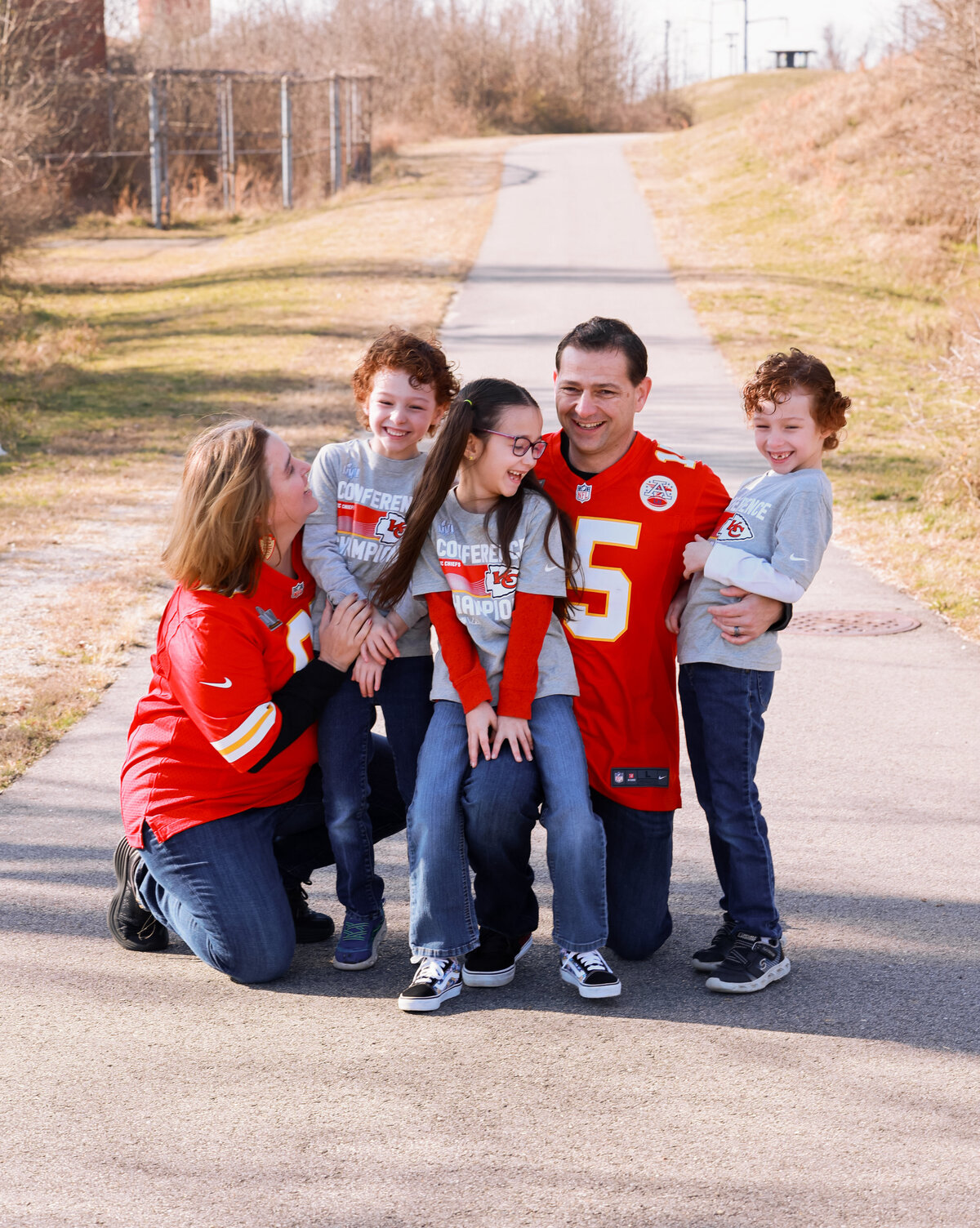 mom, dad, two sons and daughter wearing red and white football jerseys and laughing