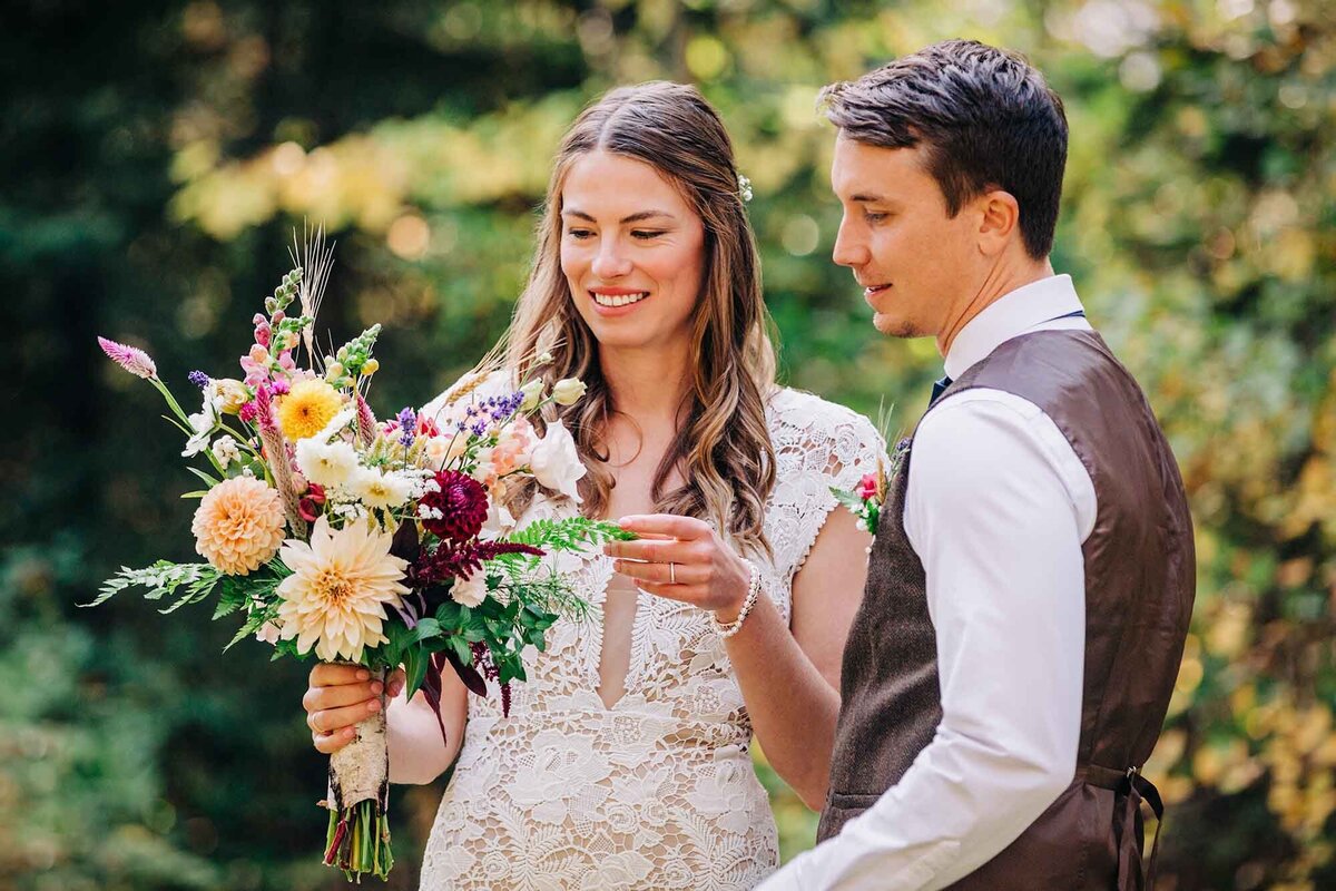 Bride and groom looking at bouquet flowers, Izaak Walton Inn, Essex, MT