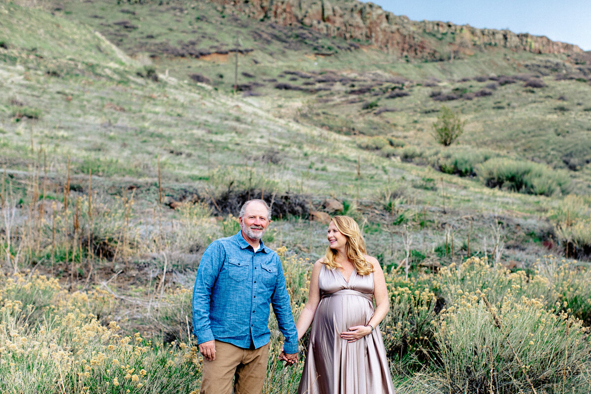 golden colorado maternity photo with pregnant woman looking at husband in front of a steep hill