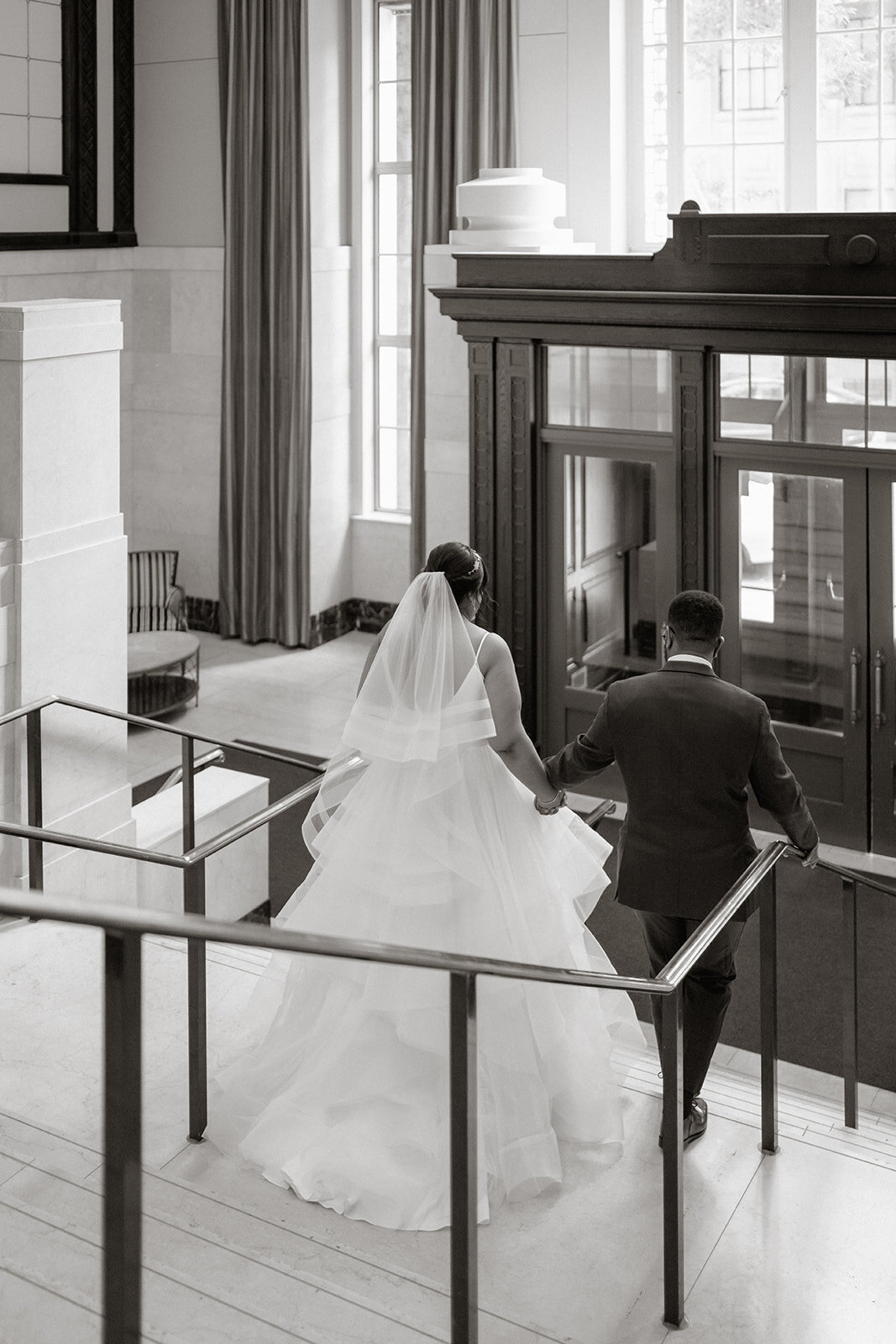 couple walks down stairs leaving venue for portraits