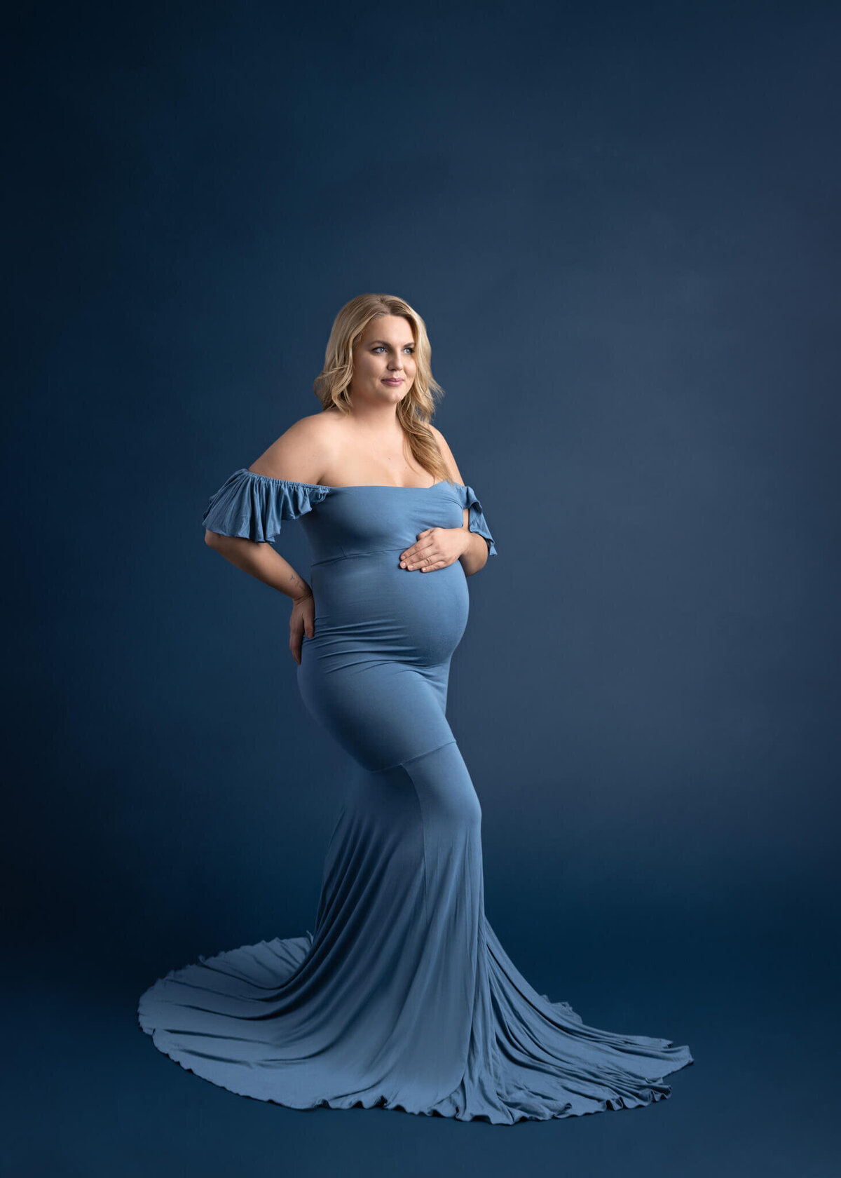 pregnant woman holding her belly wearing a blue dress
