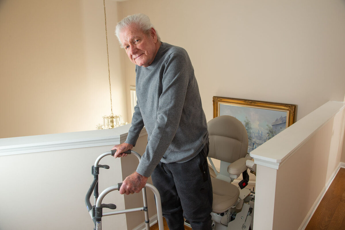 An elderly man is using a walker to get up the stairs