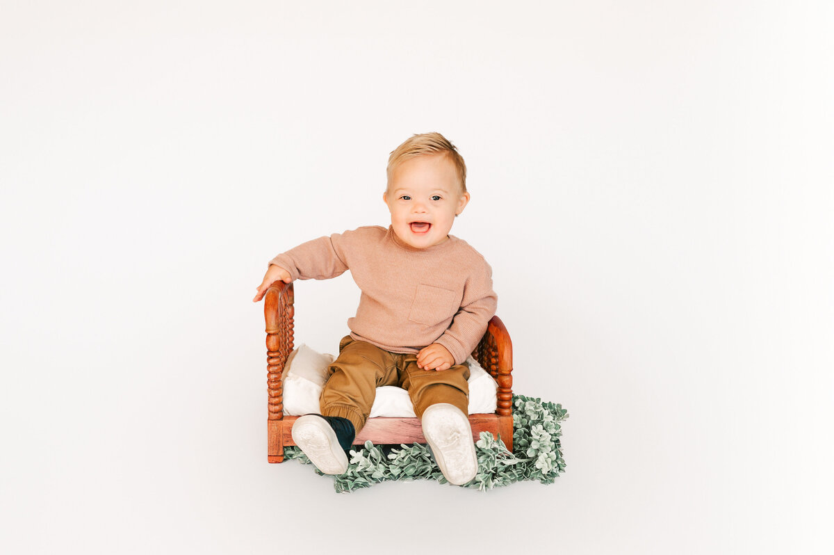 down syndrome baby boy sitting on wood bed in Springfield MO kids photography session