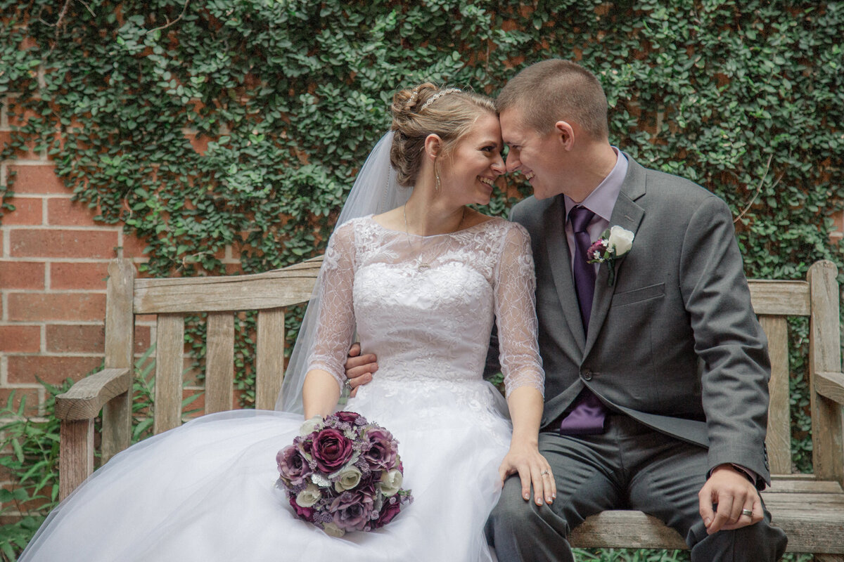 Bride & groom look deeply into each others eyes as they enjoy a quiet seated moment in the courtyard before their wedding reception.