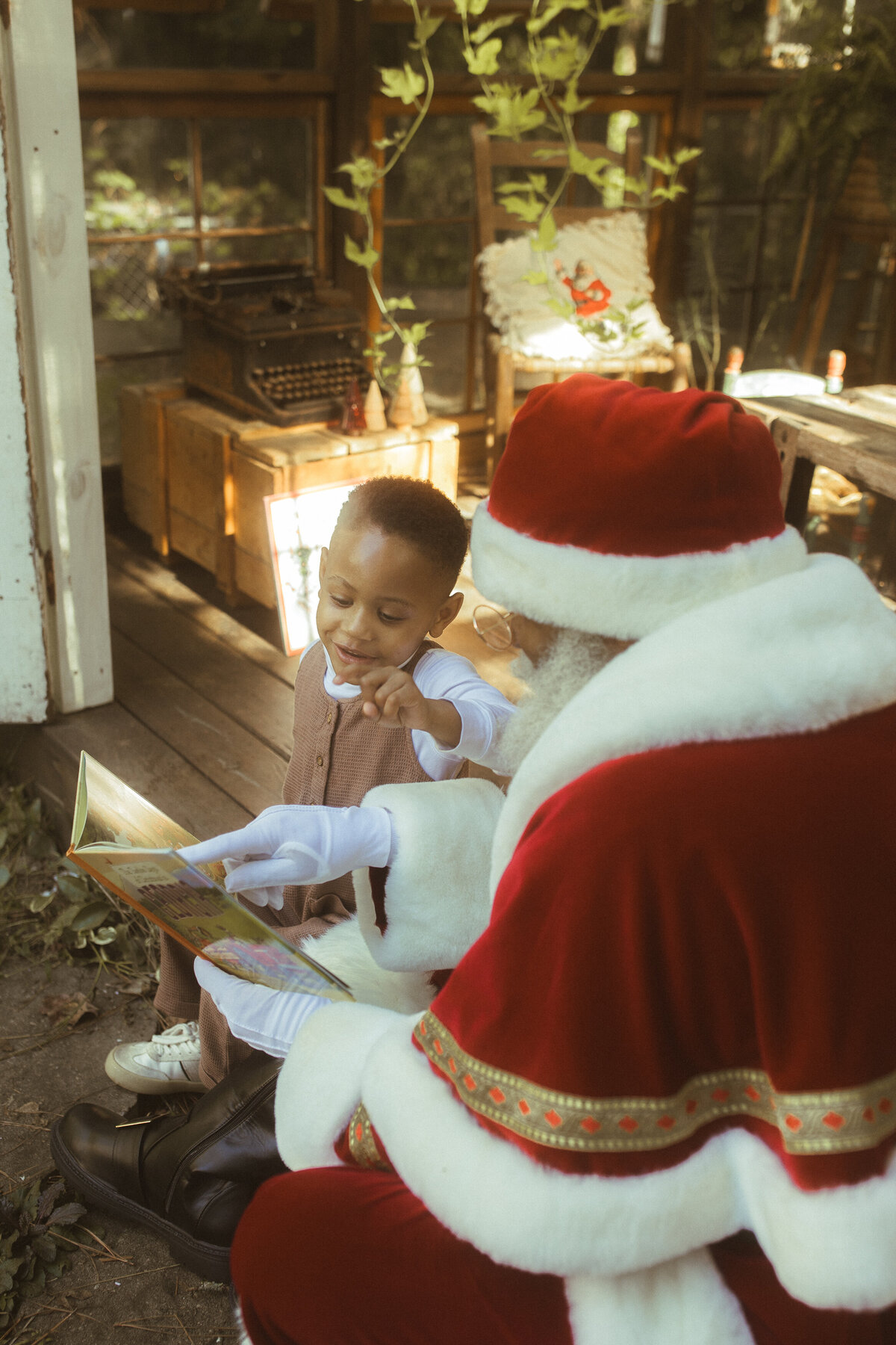 The Black Santa of Atlanta reads a book to a young boy at Das Hinterhaus.