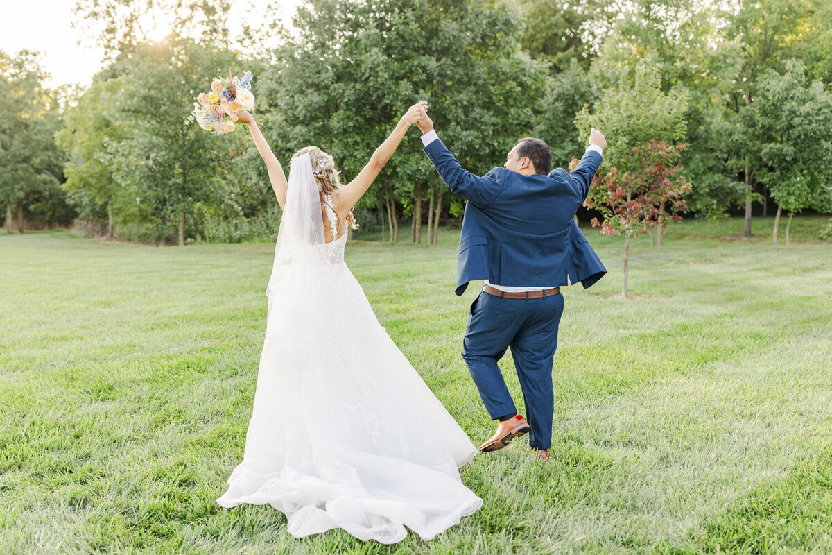 bride and groom celebrating with their arms up in the air