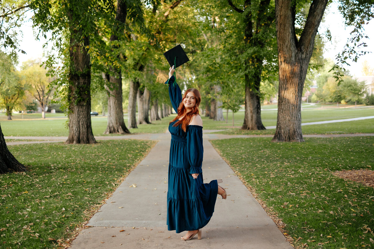 A Colorado State University graduate raises her cap in the air during her grad session in Fort Collins, Colorado.