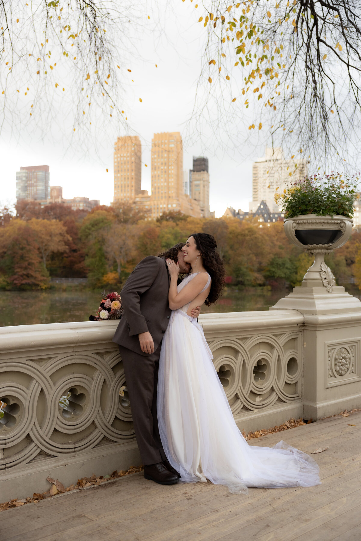 The couple holding hands and smiling as they walk through a peaceful Central Park path.