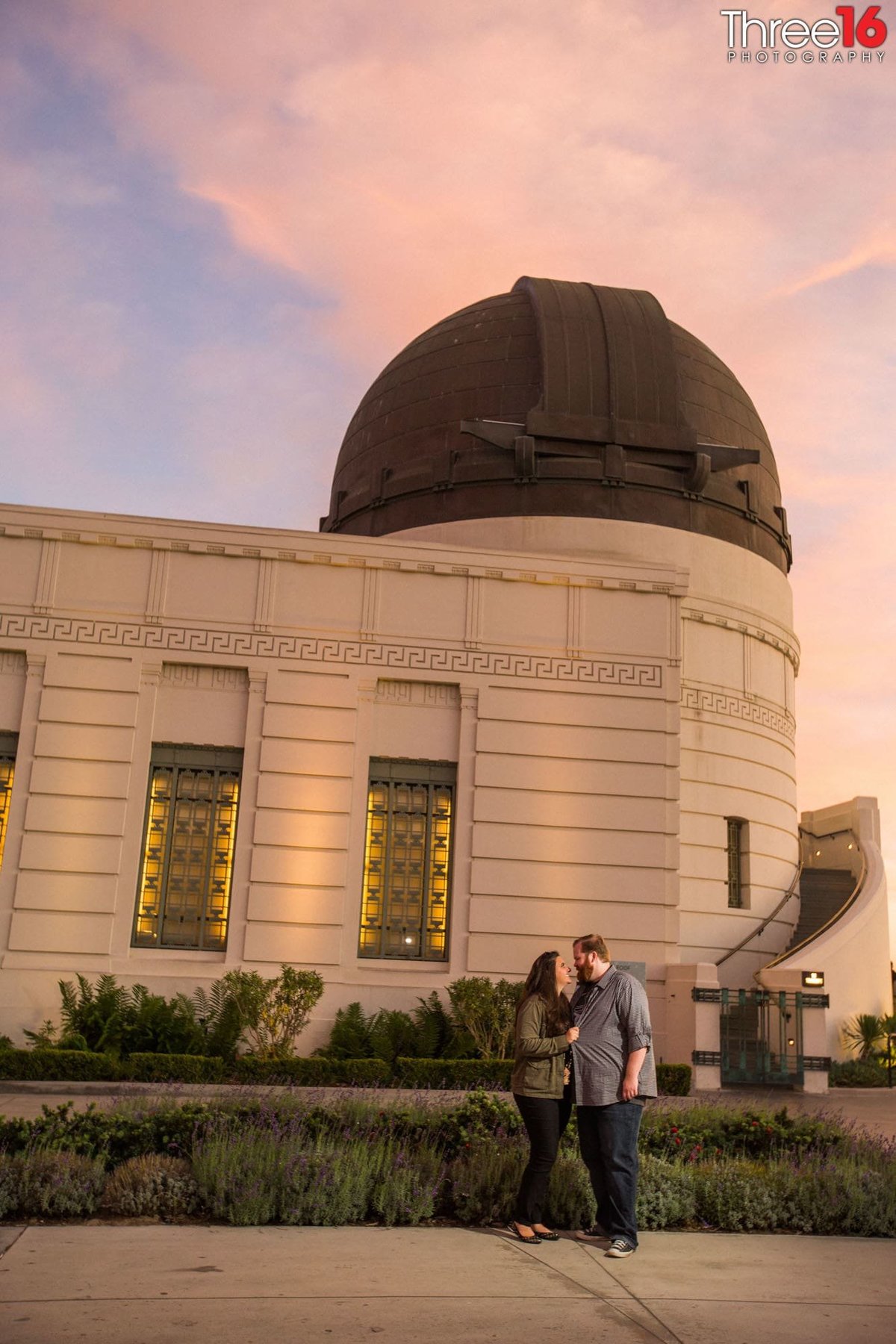 Engaged couple get cozy in front of the Griffith Observatory Planetarium