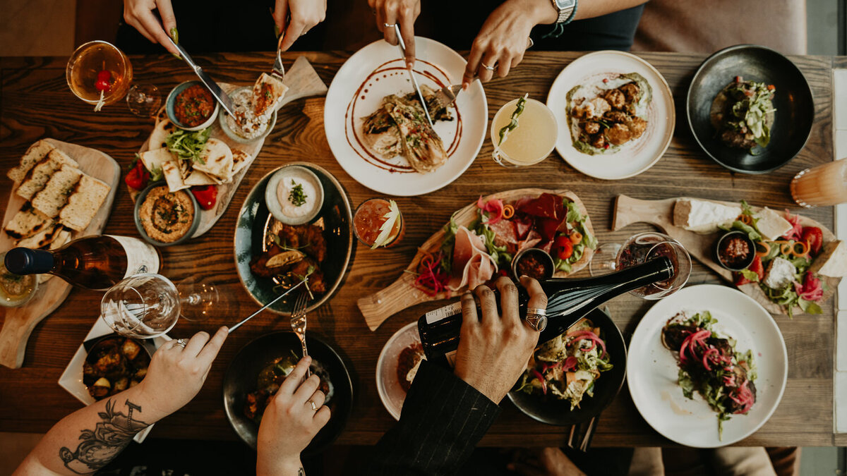 people eating sharing platters and drinking wine.