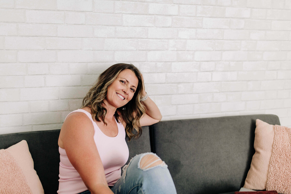 April posed on sofa with one knee up smiling