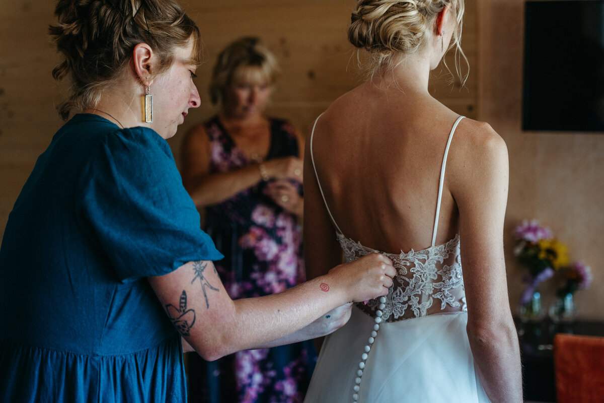 Bride’s mother adjusting wedding gown strap