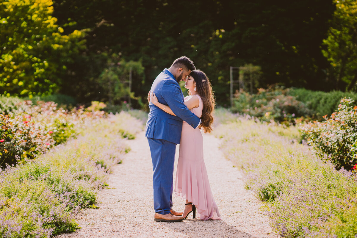 A couple embracing in the garden area on a walkway at the planting fields arboretum in oyster bay