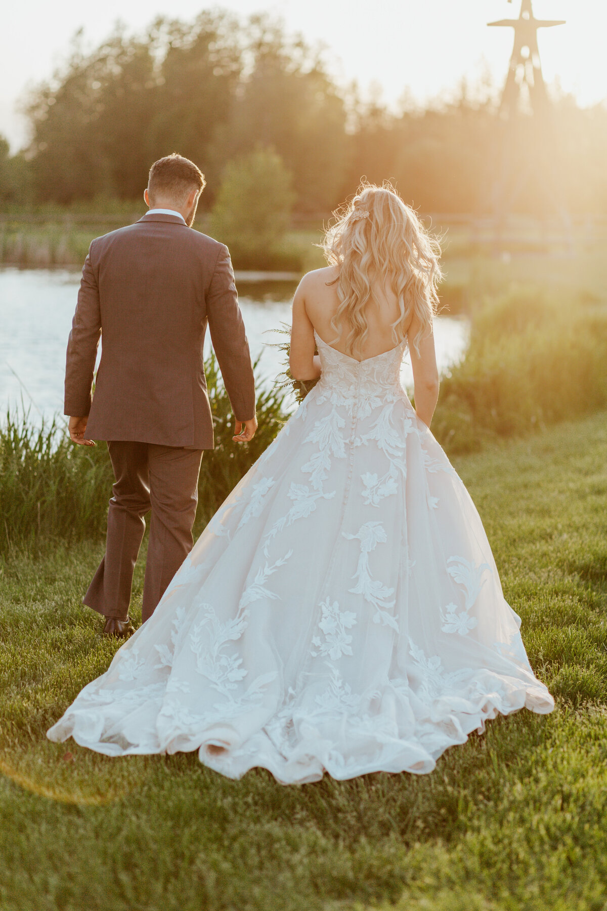 bride and groom standing by lake