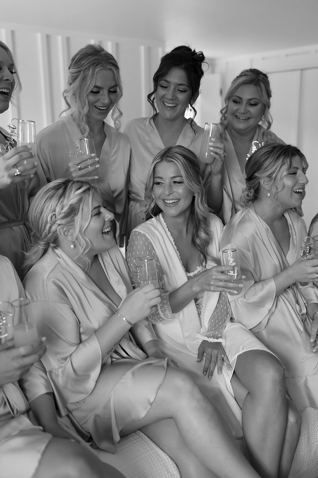 black and white photo of bridesmaids on bed with champagne at windridge estate