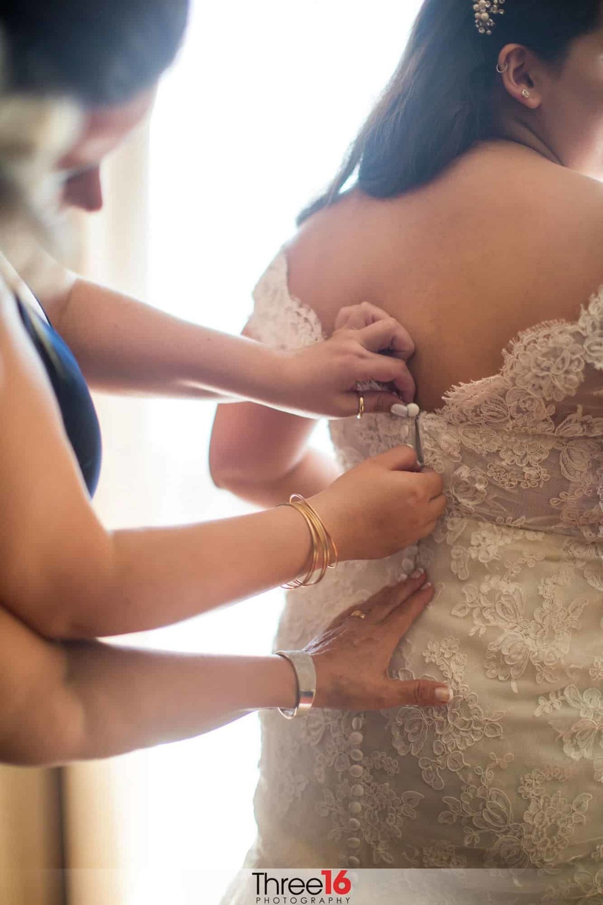 Bride having her dress buttoned up before the ceremony