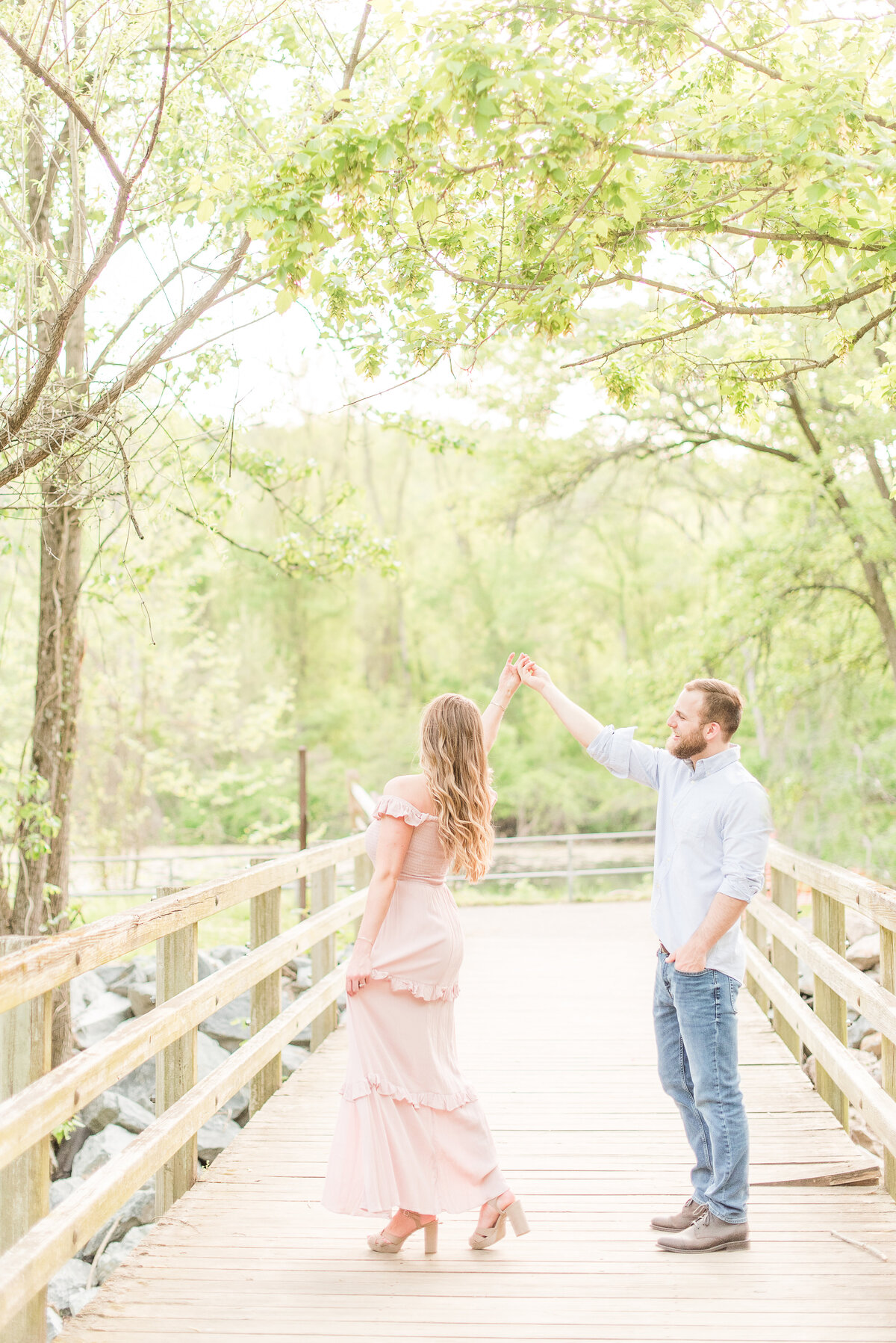 couple twirling on bridge pink maxidress and blue button up shirt