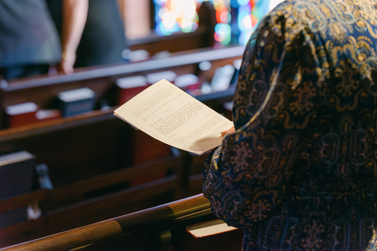 Close-up of guest holding custom ceremony program during wedding service in San Antonio