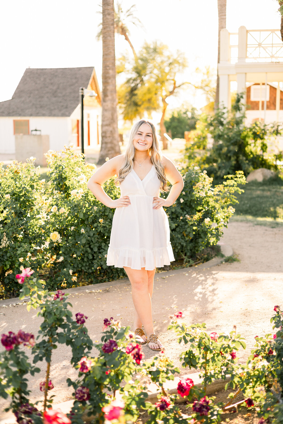 Senior girl stands among rose garden at Sahuaro Ranch Park in Glendale Arizona.