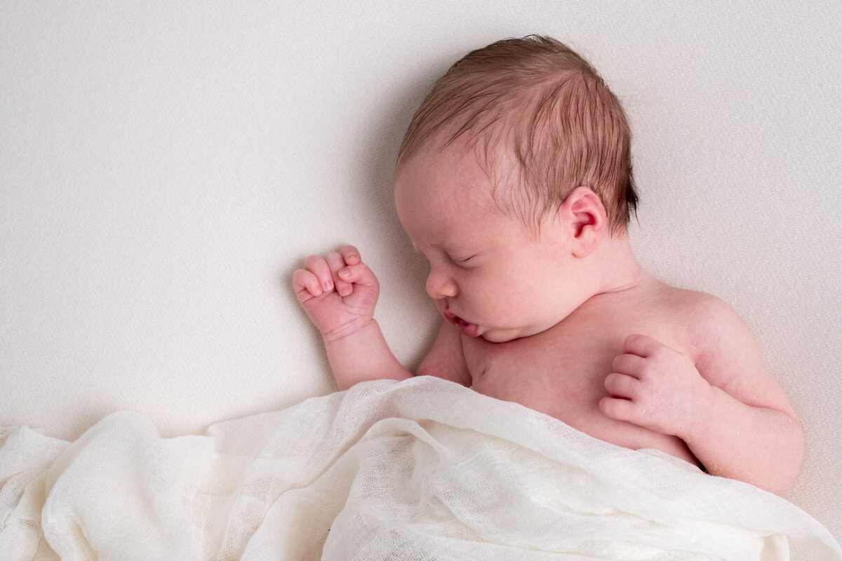 Newborn fotoshoot met een zachte crèmekleurige achtergrond. Perfect om de eerste momenten met je baby vast te leggen in een natuurlijke en tijdloze stijl.