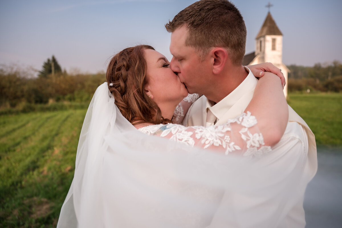 wedding couple kiss in front of a church