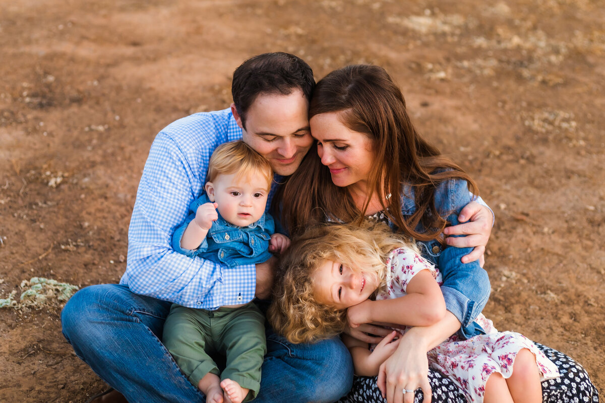 Family Photographer, a young family of four snuggle together outside