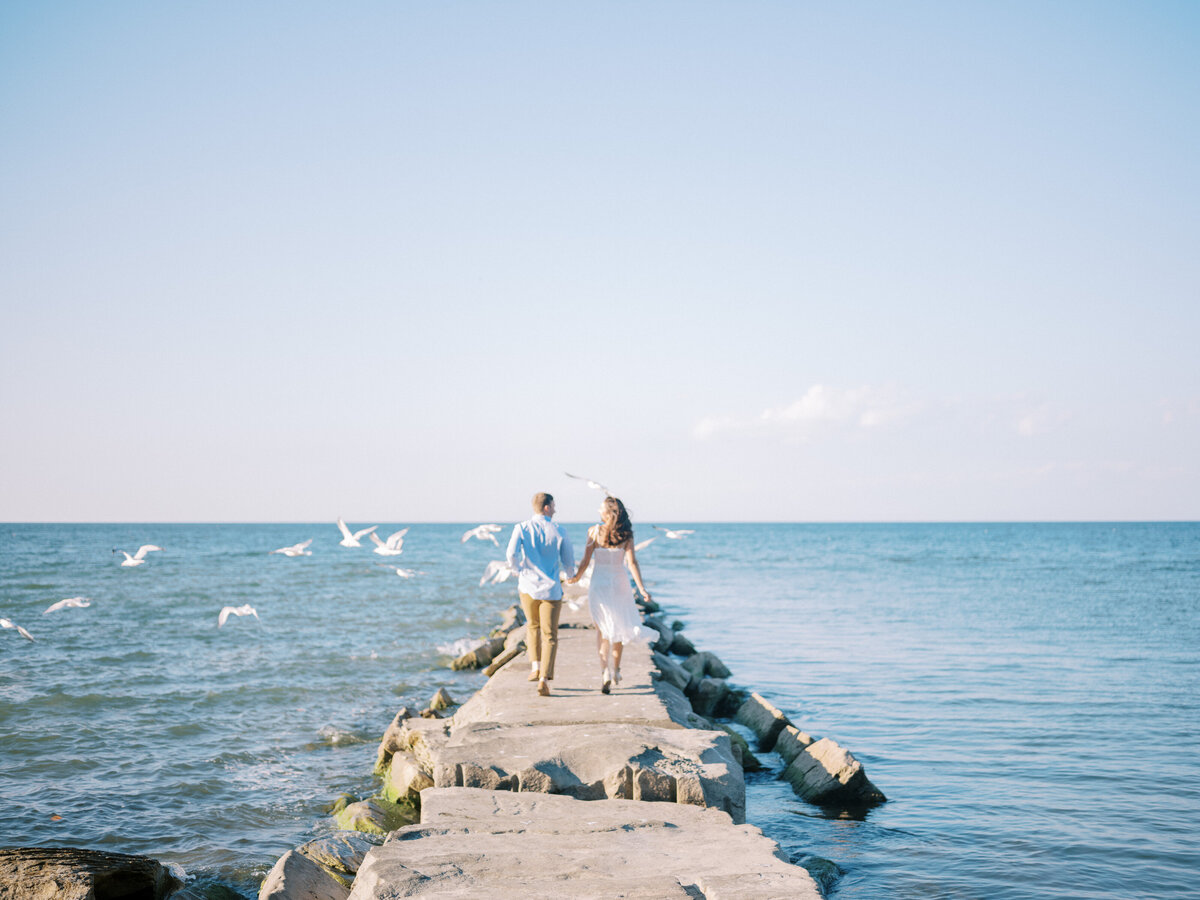 couple-running-on-pier-with-seagulls-flying