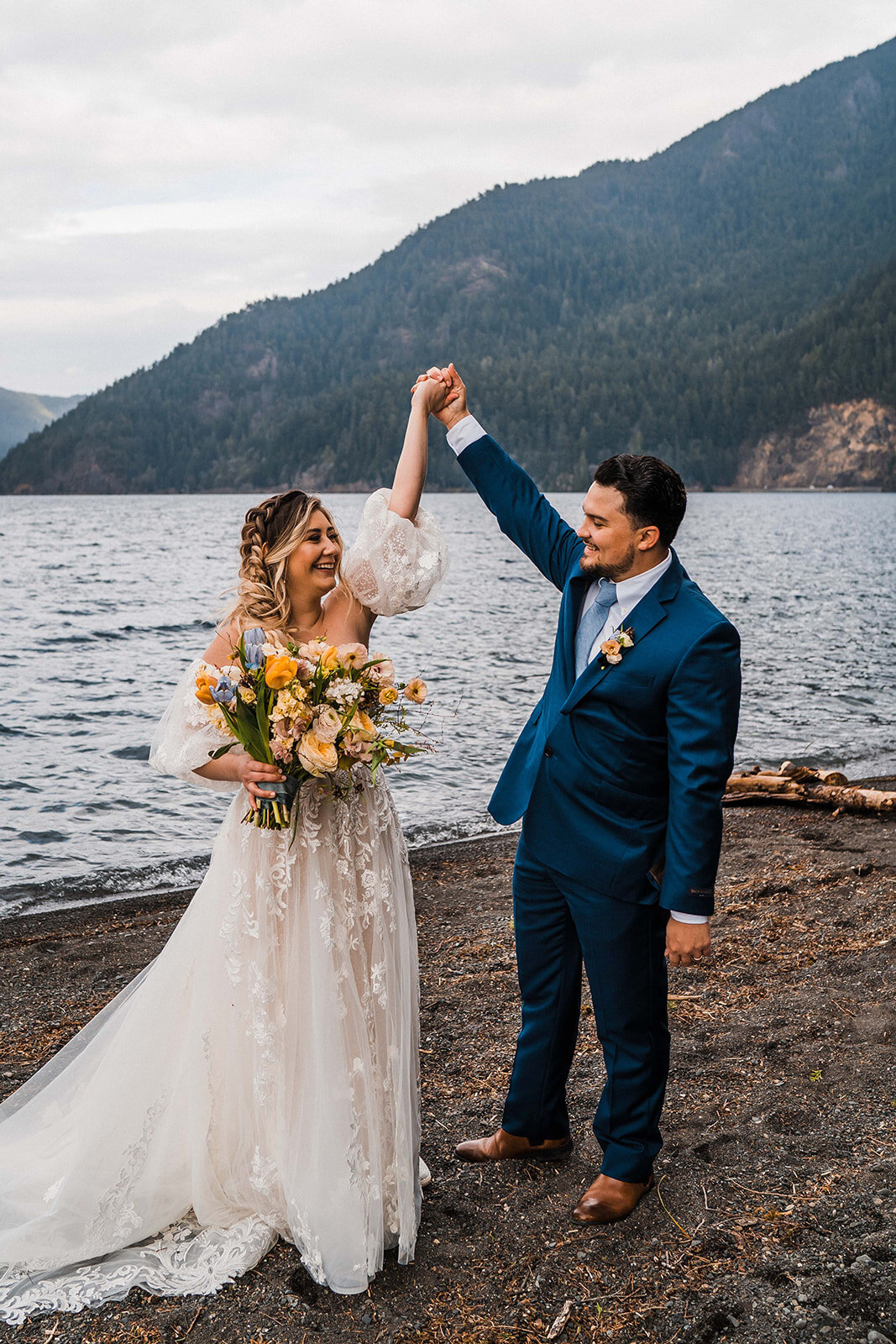 Bride & groom holding hands and raising them in the air during elopement on Lake Crescent in Olympic National Park!